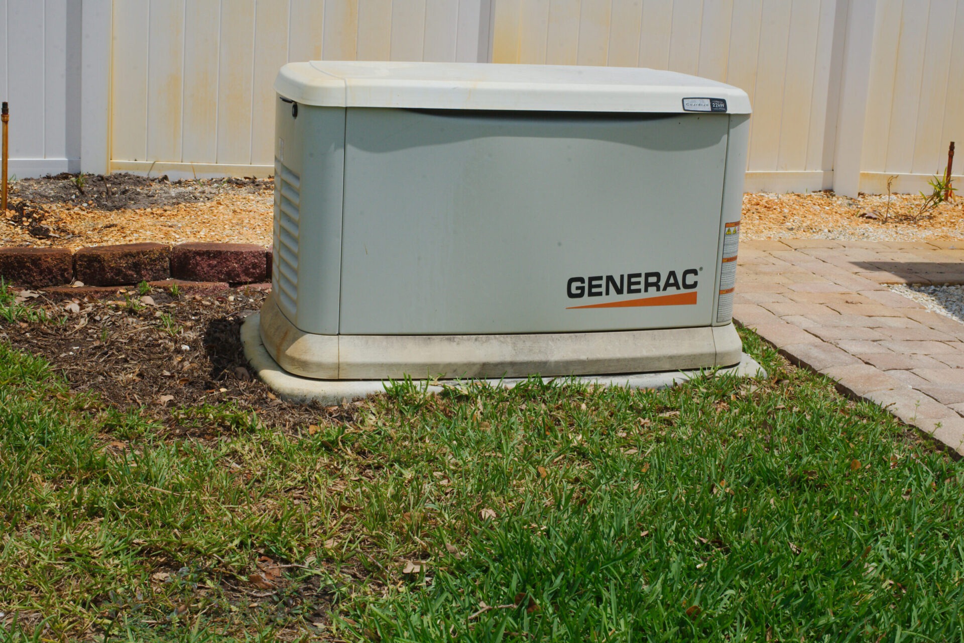 Residential Backup Generator Installed in Green Backyard Near White Fence. Editorial Use Only April 29, 2025 Largo, FL, USA. Outdoor installation of a residential backup Generac generator situated in